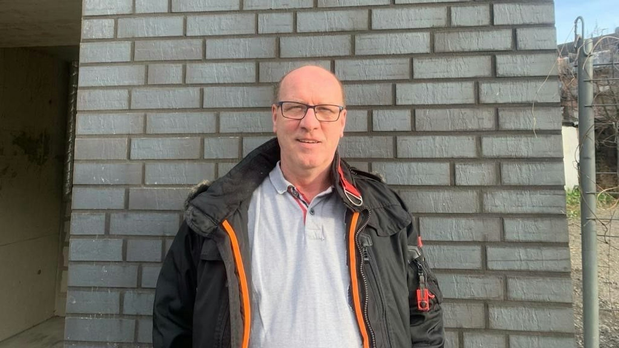 Michael Klein ist 1. Vorsitzender des 1. Dartteam Köln von 1998 e.V., steht vor einer geklinkerten Wand.