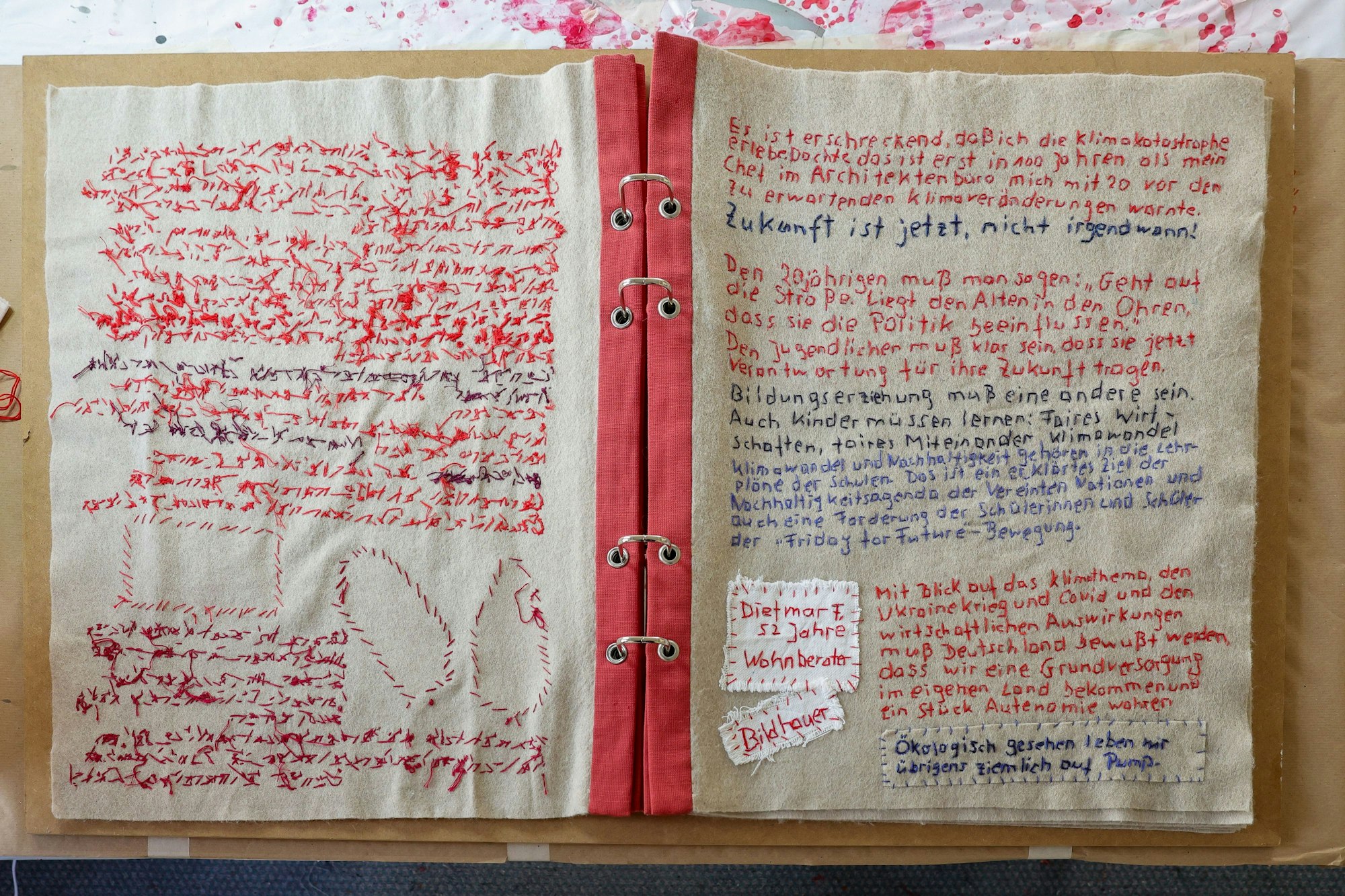 Eine voll geschriebene Seite aus einem großen Buch. Der Text ist gestickt.