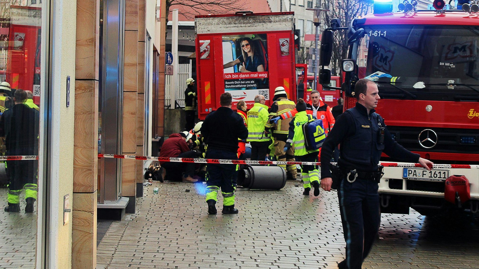 29.12.2023, Bayern, Passau: Einsatzkräfte von Feuerwehr und Rettungsdienst stehen in der Innenstadt am Einsatzort. Ein Lastwagen ist in der Passauer Innenstadt in eine Fußgängergruppe gefahren und hat dabei mehrere Menschen verletzt und eine Frau getötet. Auch der Lastwagenfahrer sei auf dem Weg ins Krankenhaus, sagte ein Polizeisprecher. Foto: -/Zema Medien/dpa +++ dpa-Bildfunk +++