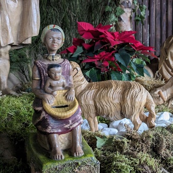 Eine Missionsspardose (li.), die eine dunkelhäutige Frau mit einem Kind auf dem Schoß darstellt, ist Teil der Kirchenkrippe der Pfarrkirche St. Martin in Nettersheim.
