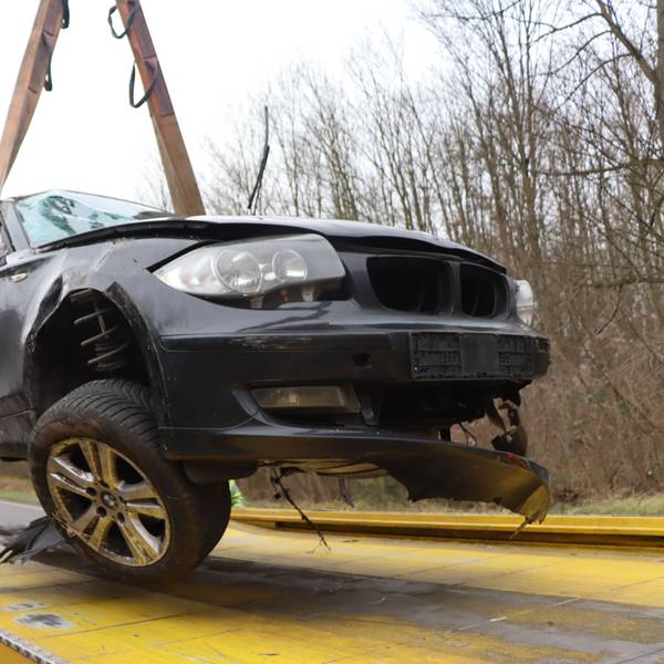 Ein bei einem Unfall schwer beschädigter BMW wird auf einen Abschleppwagen gehievt.