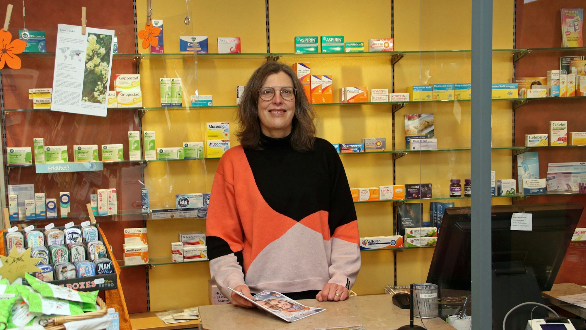 Eine Frau hinter der Verkaufstheke einer Apotheke.
