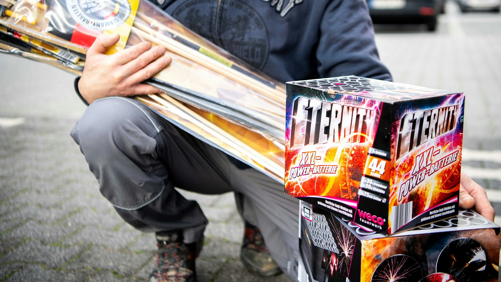Ein Mann, dessen Gesicht nicht zu sehen ist, zeigt das Silvesterfeuerwerk, das er gekauft hat..