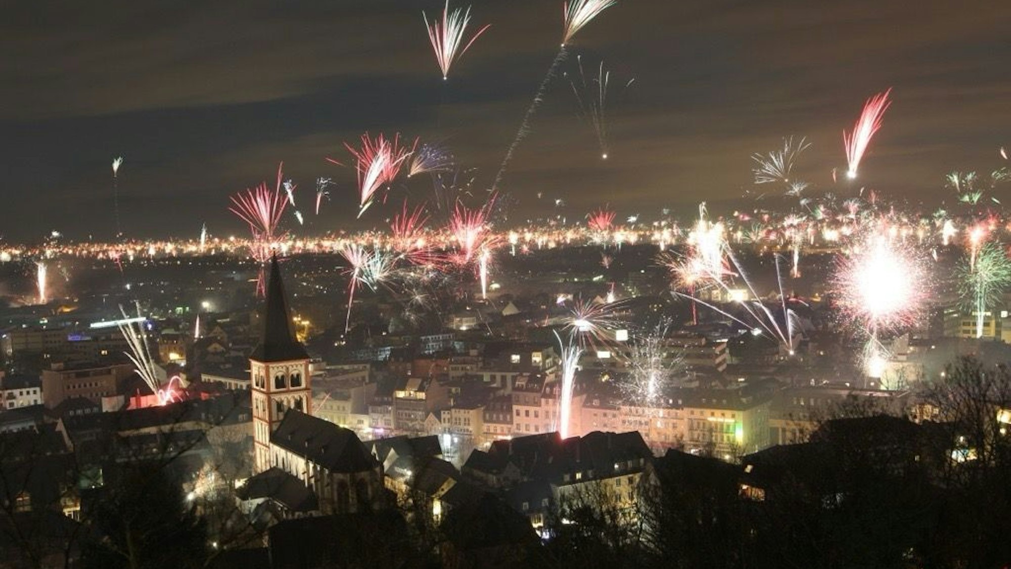Silvesterfeuerwerk in der Ebene, gesehen von einem höheren Standort.