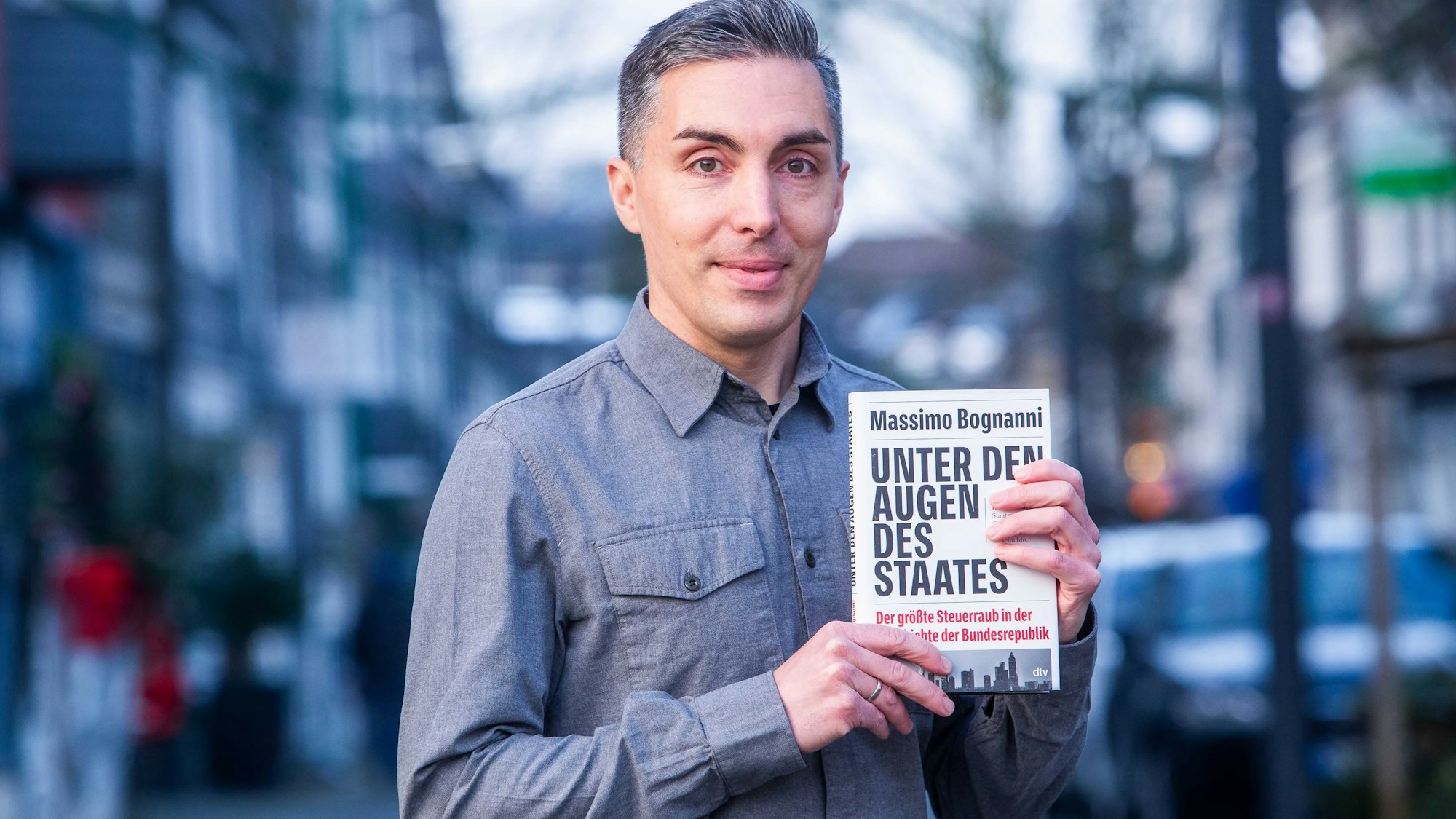 Das Foto zeigt Massimo Bognanni mit seinem Buch „Unter den Augen des Staates“.