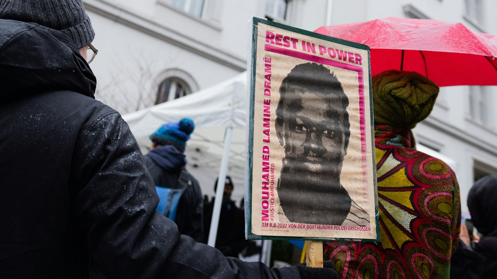 Demonstranten stehen mit Plakaten, die das Porträt des 16-jährigen Senegalesen Mouhamed Drame zeigen, vor dem Dortmunder Landgericht. (Archivbild)