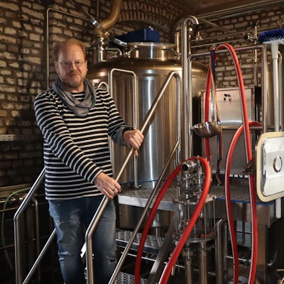 Zu sehen ist ein Mann, der neben Edelstahltanks steht.