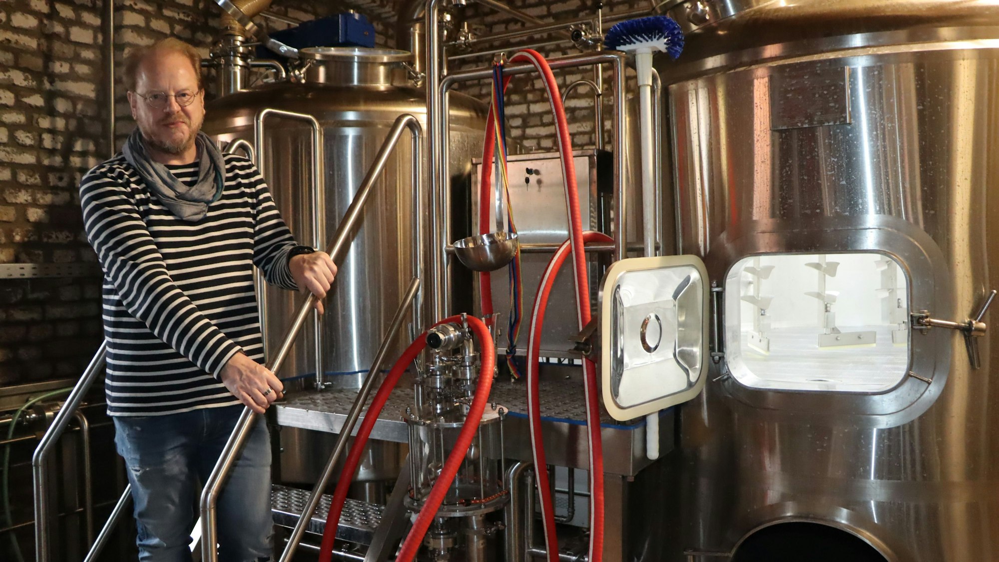 Zu sehen ist ein Mann, der neben Edelstahltanks steht.