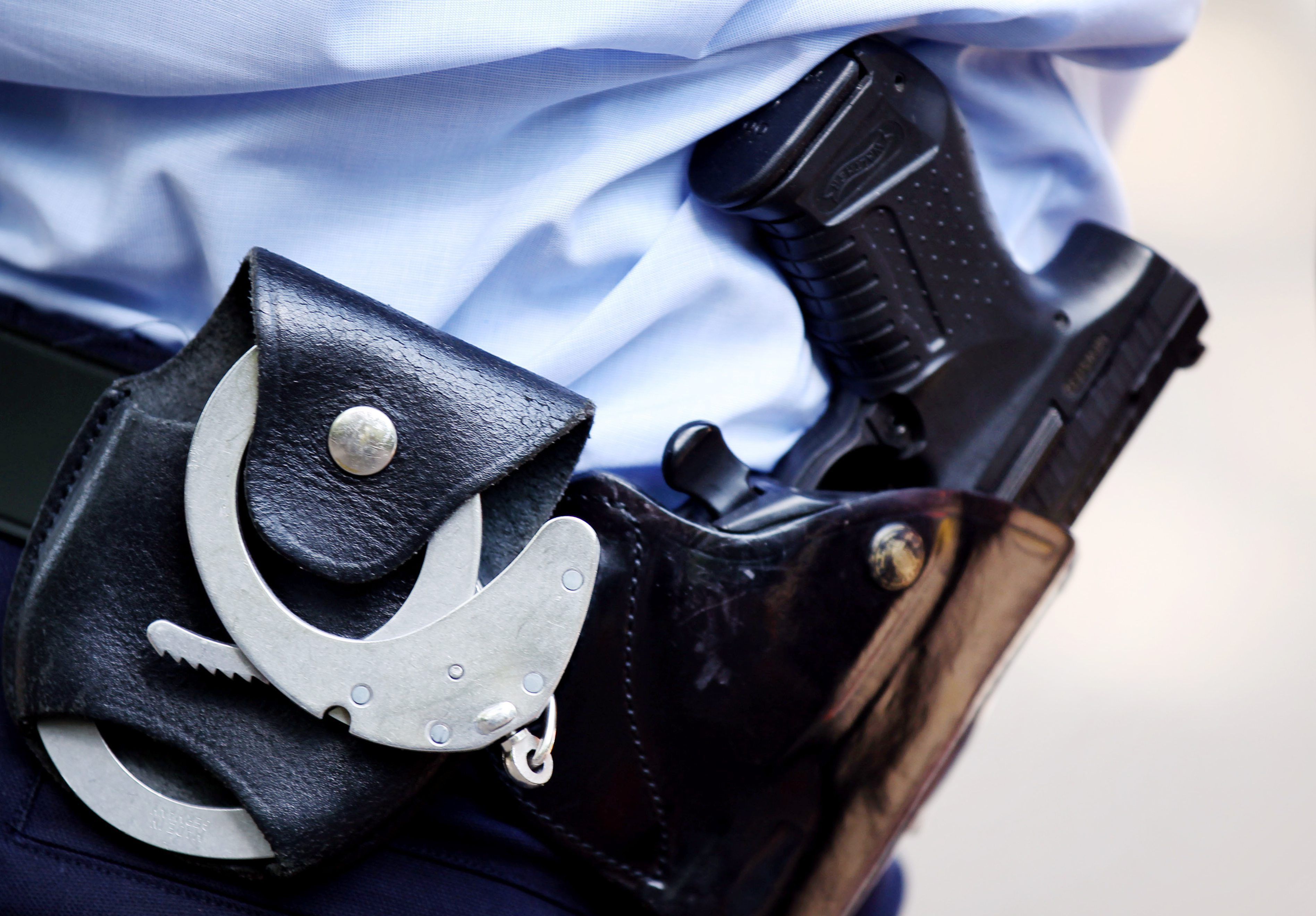 Ein Polizist mit Handschellen und Pistole am Gürtel steht in Köln.