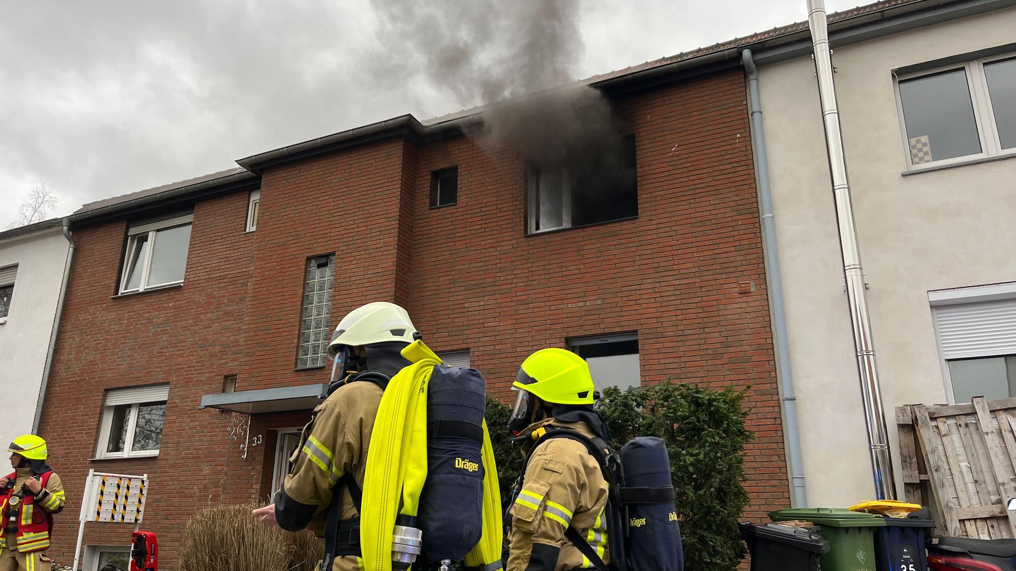 In einer Küche einer Wohngruppe für Jugendliche hat es gebrannt, Feuerwehrleute stehen als Rettungstrupp für ihre Kameraden vor dem Haus.
