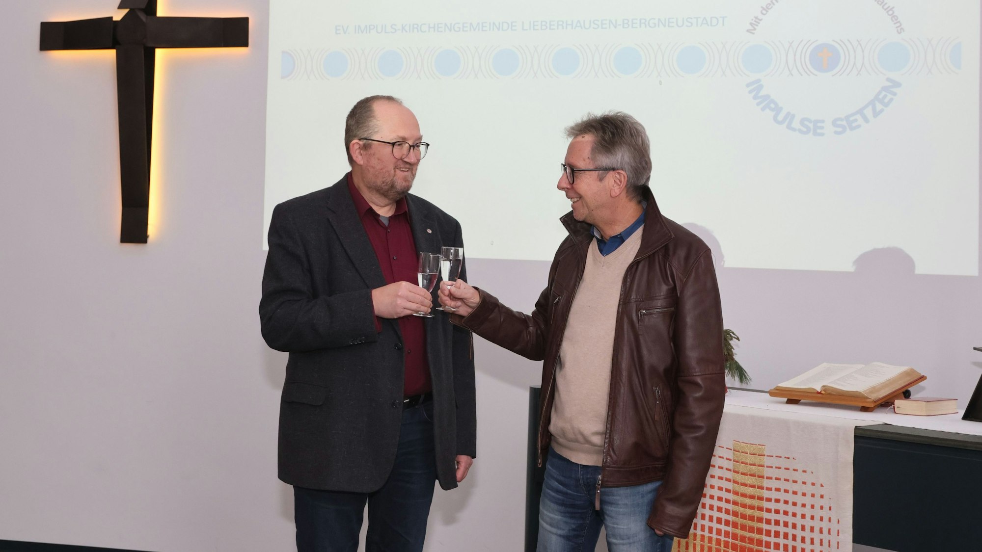 Zwei Pfarrer stoßen mit Sektgläsern an.