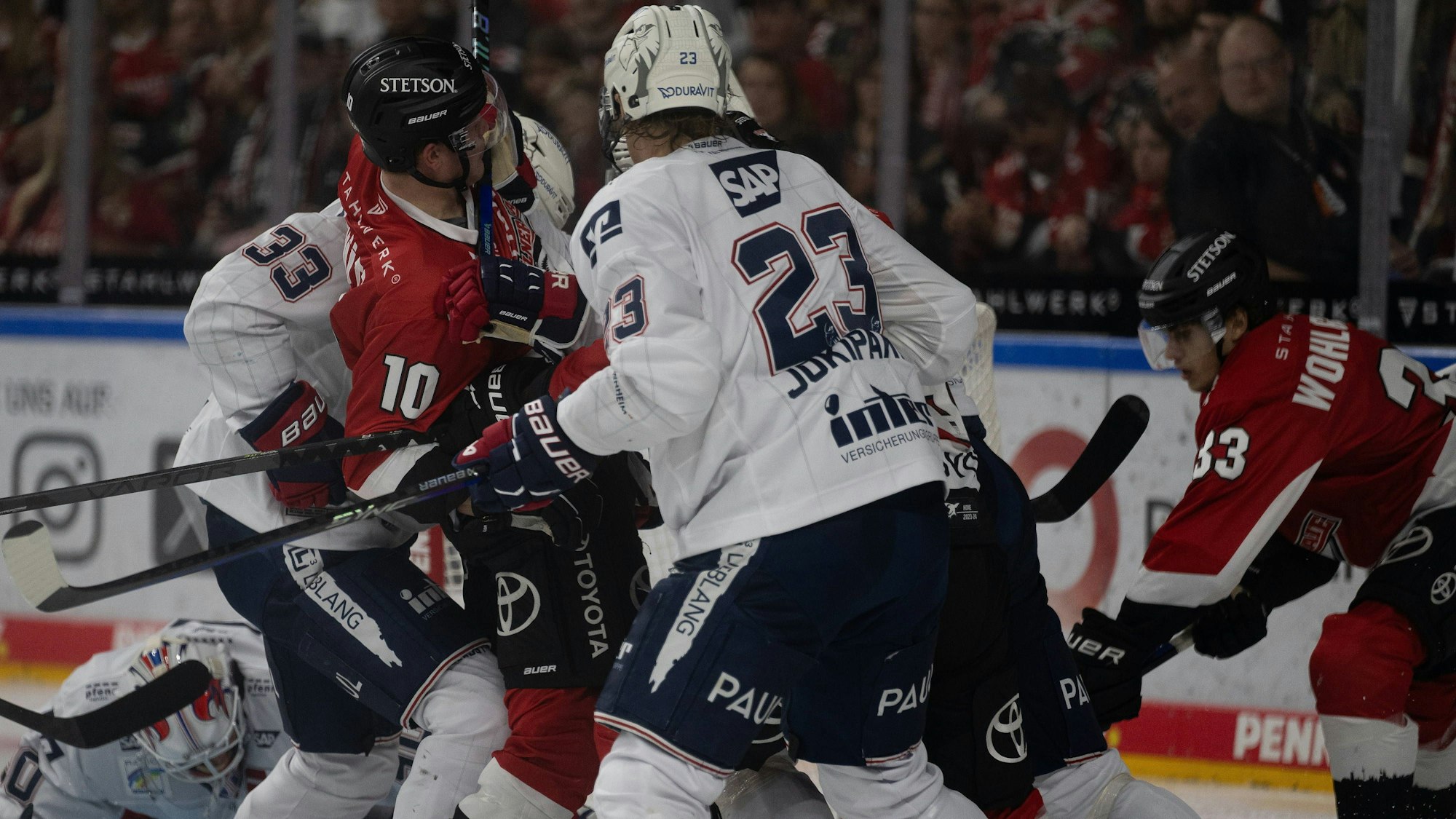 Eishockey-Spieler der Kölner Haie und Mannheimer Adler im Gerangel. Ein Spieler ist am Boden.