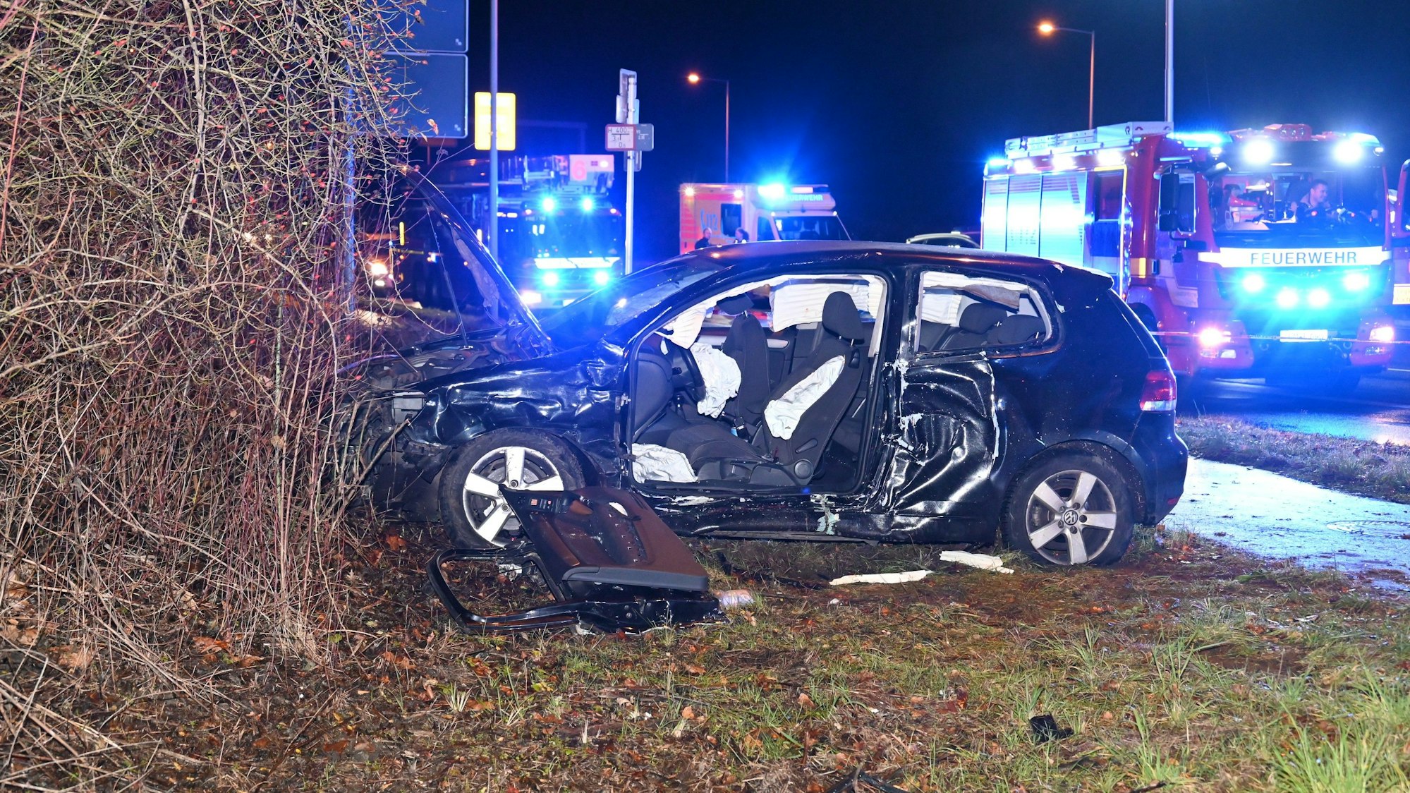 Ein VW Golf steht vor einem Gebüsch. Die Seite des Wagens ist zerstört, die Tür herausgerissen.
