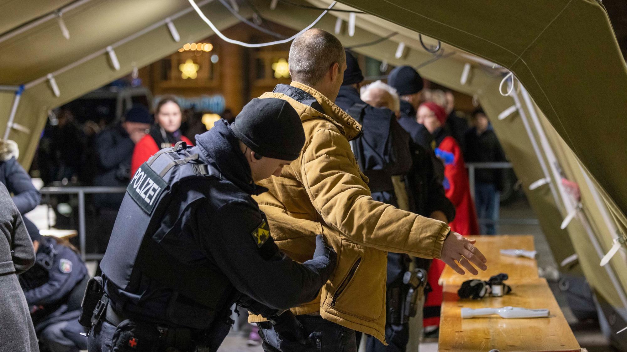 Ein Polizist tastet die Kleidung eines Gottesdienstbesuchers ab.