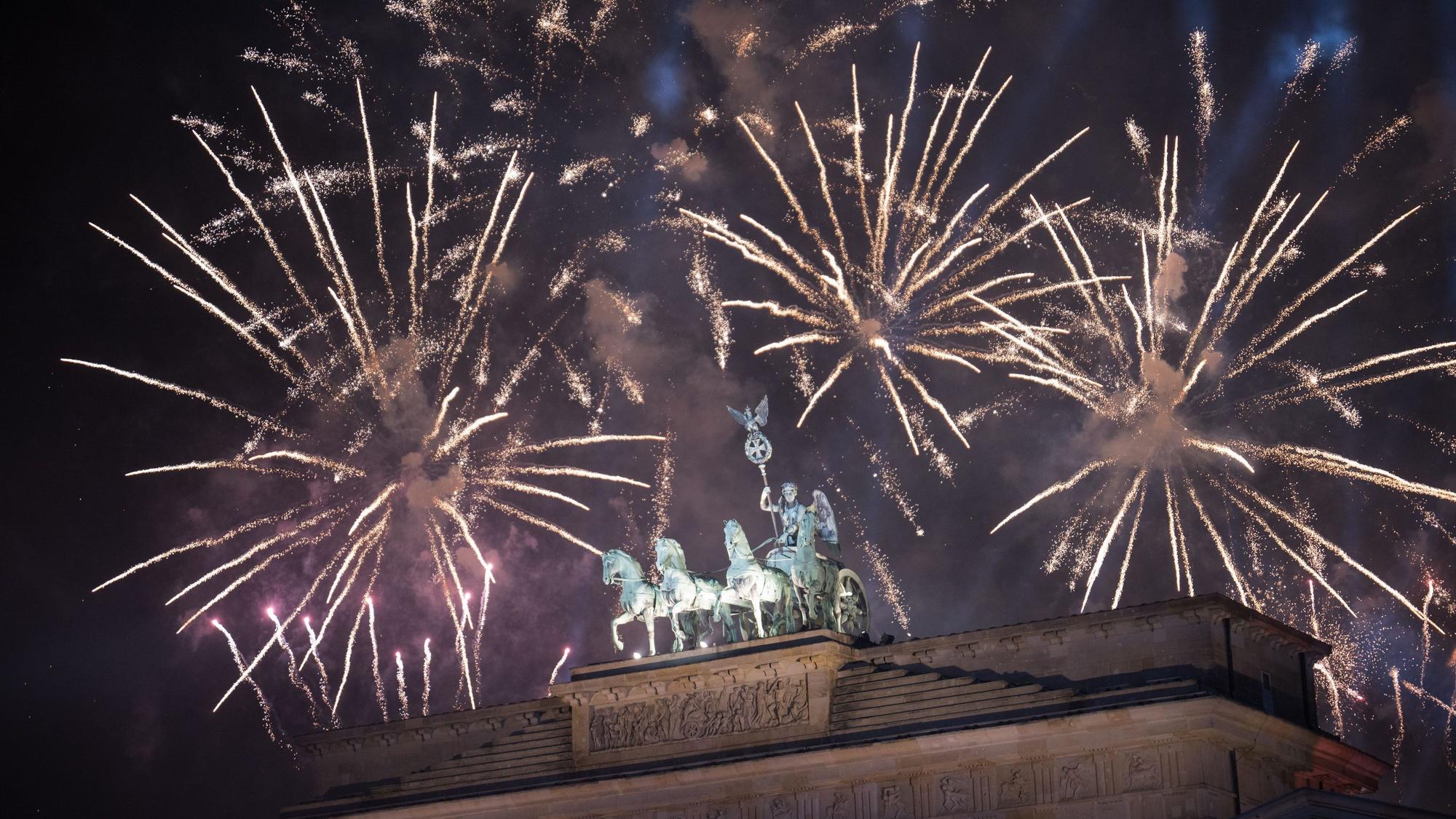 Feuerwerk zum Jahreswechsel steigt während der Feier „Silvester am Brandenburger Tor“ hinter dem Brandenburger Tor auf.