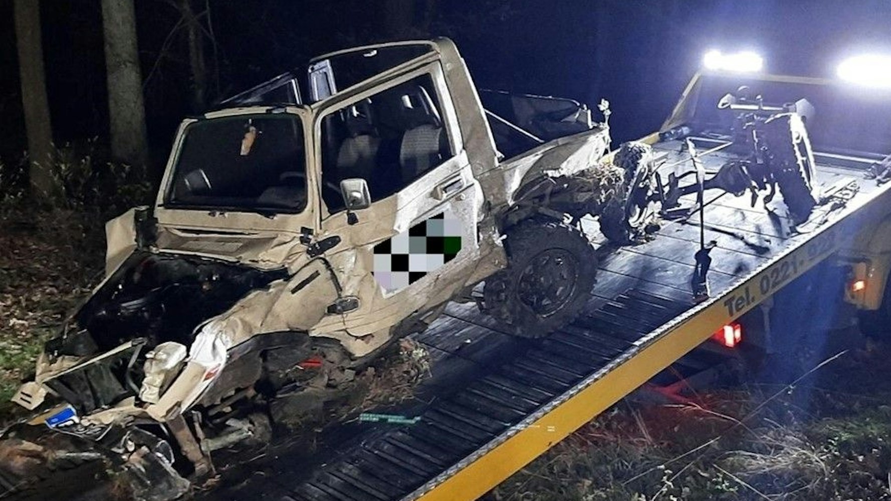 Ein total beschädigtes Auto wird auf einen Abschleppwagen gezogen,