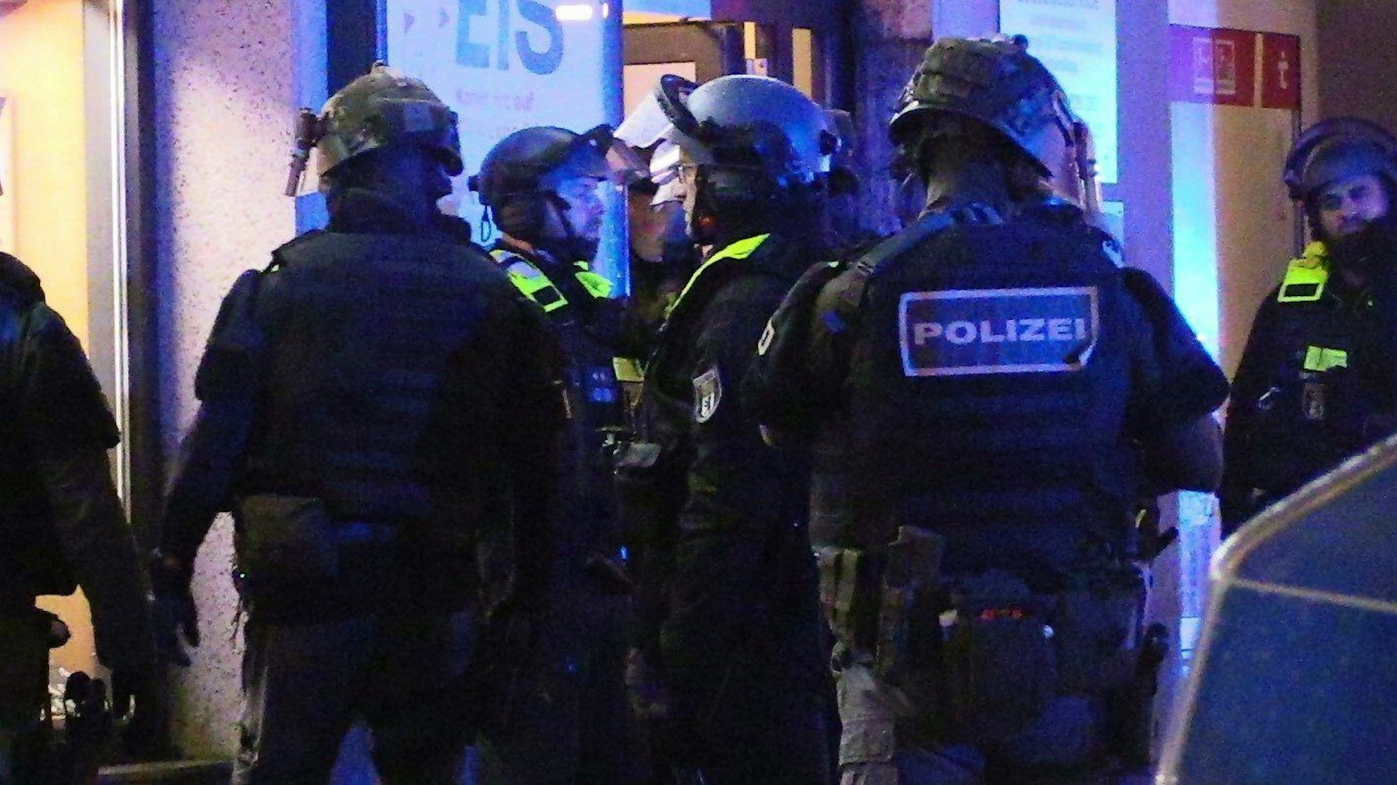 Polizei steht vor einem Hauseingang.