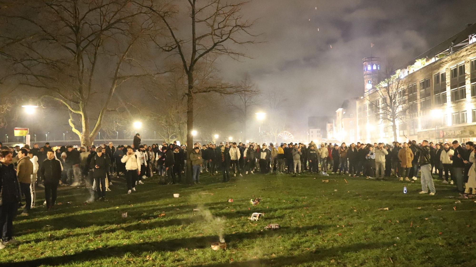 An der Frankenwerft, direkt am Rhein, werden auch schon vor Mitternacht reichlich Silvesterknaller abgefeuert. Die Rheinuferwiesen sind voller Menschen.