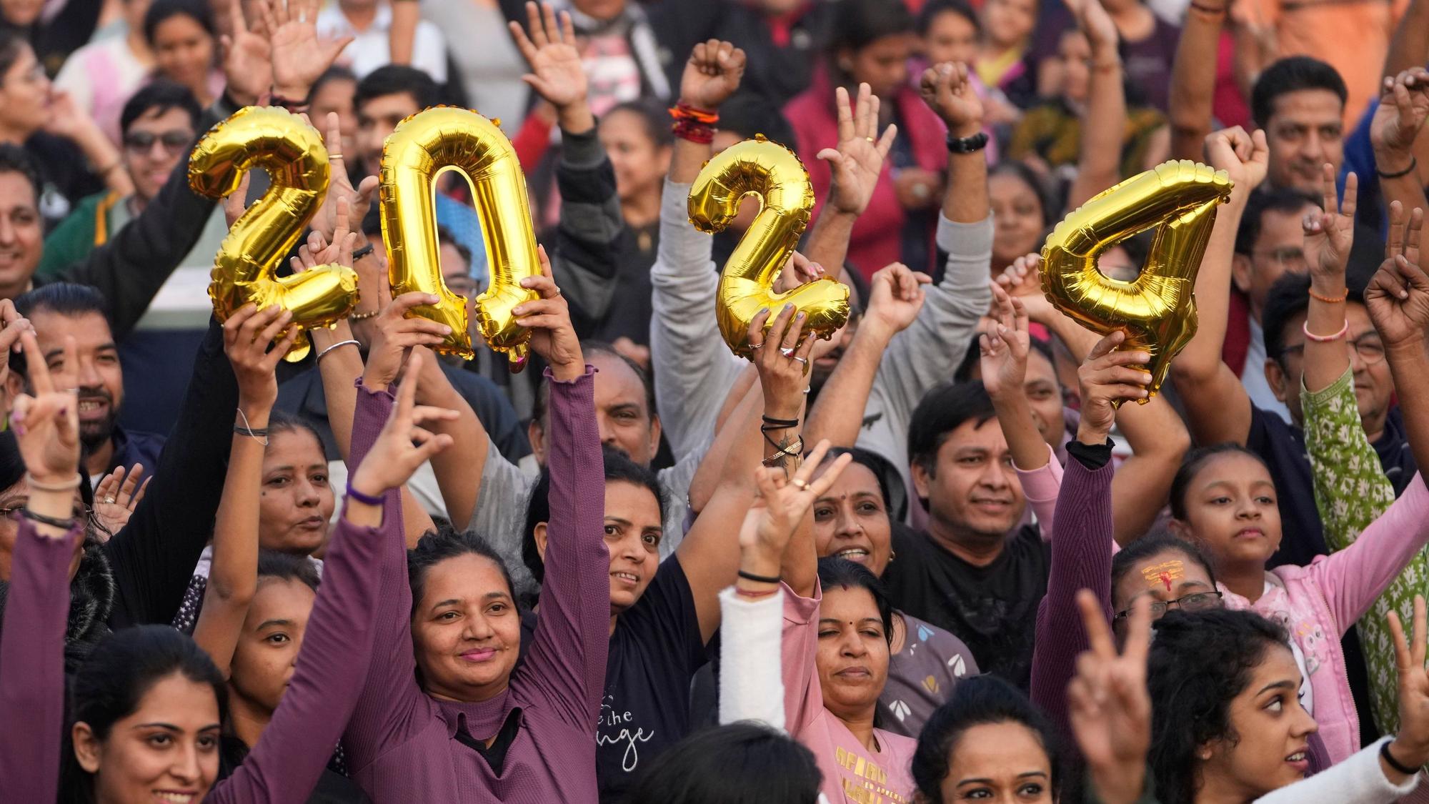 Menschen halten die Zahl 2024 und jubeln während einer Veranstaltung zur Verabschiedung des Jahres 2023 und zur Begrüßung des neuen Jahres in Ahmedabad (Indien).