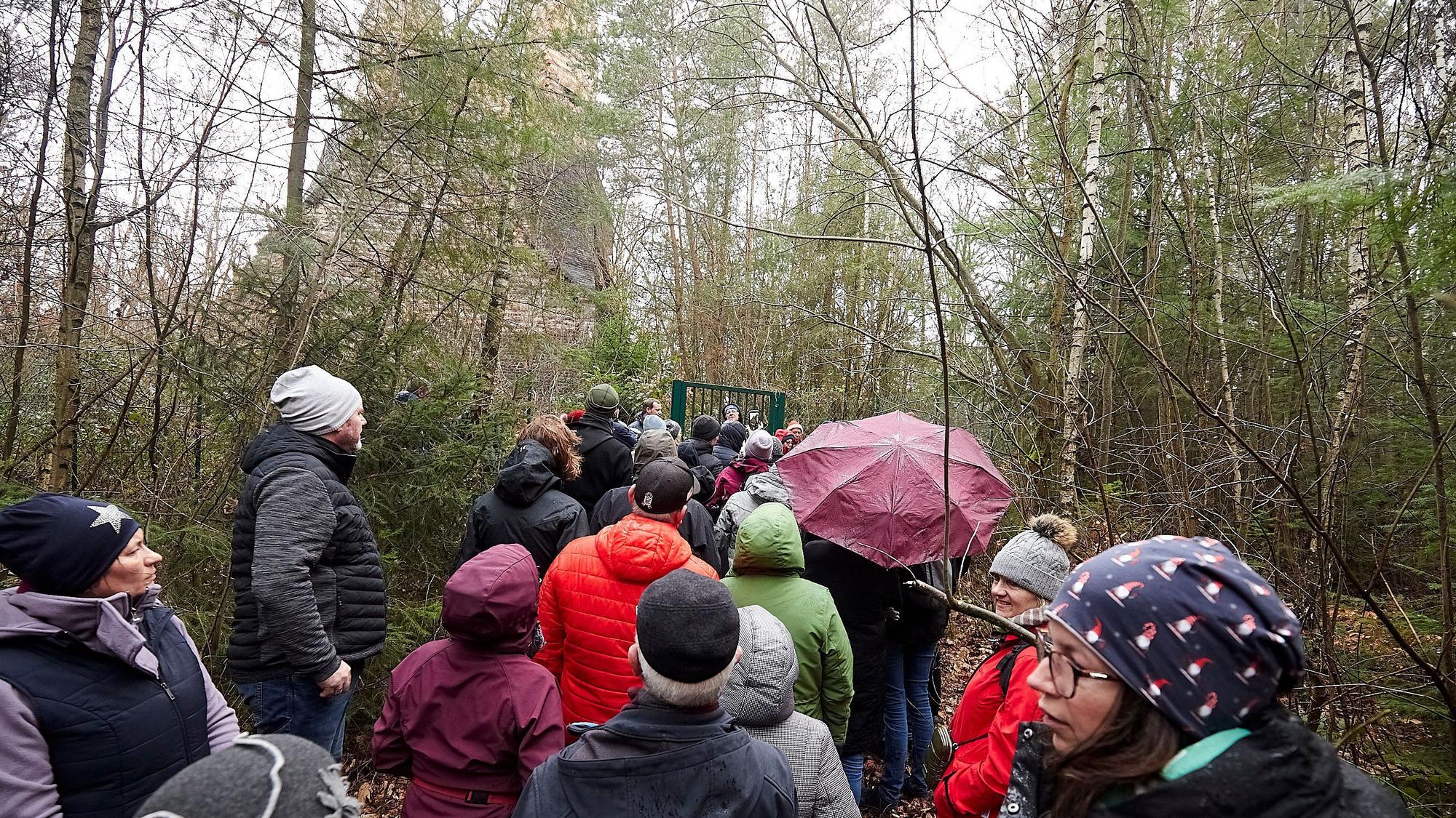 Das Bild zeigt einer Wandergruppe, die am Fundament des einst so hohen Schlots Halt gemacht hat.