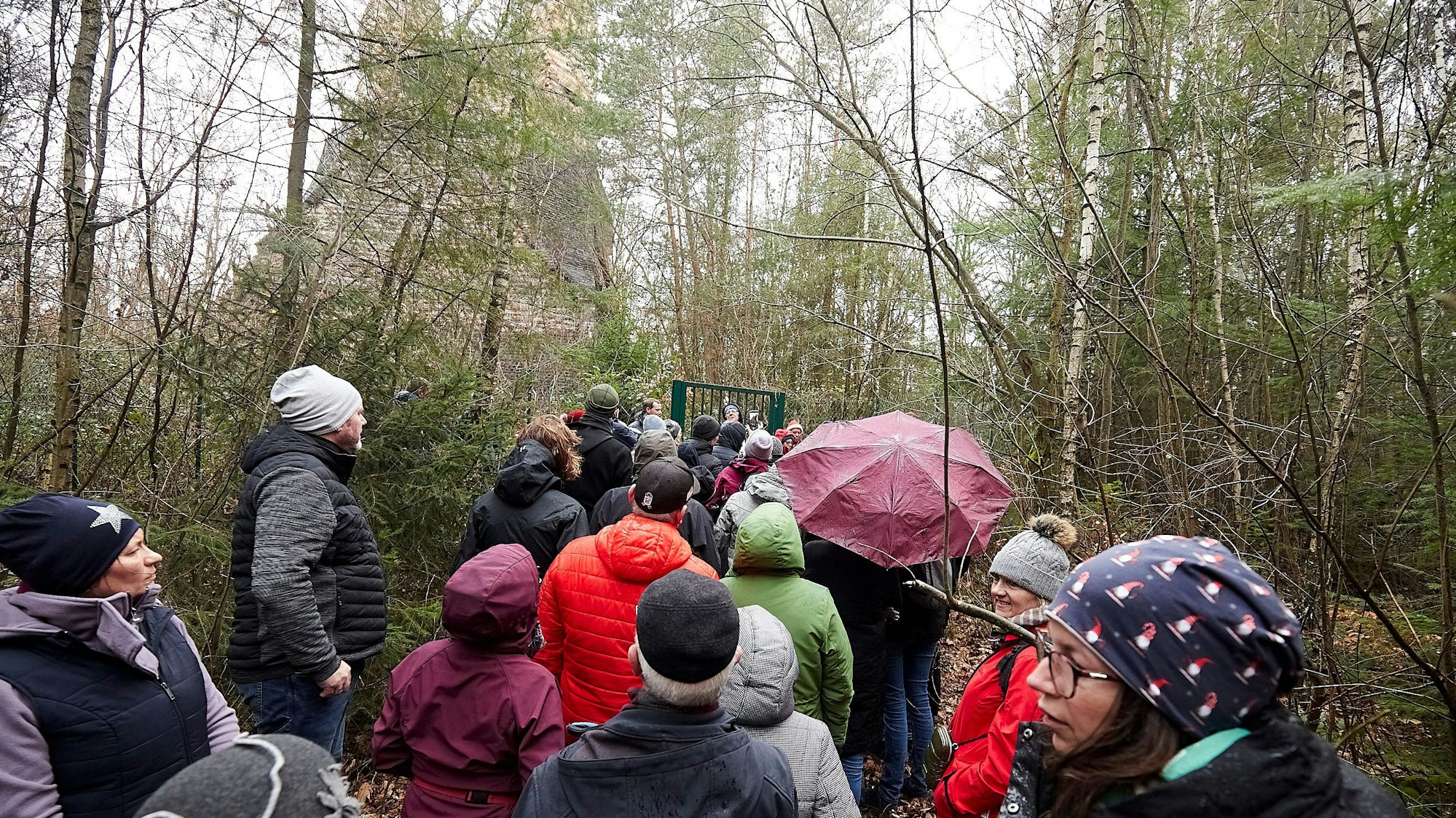 Das Bild zeigt einer Wandergruppe, die am Fundament des einst so hohen Schlots Halt gemacht hat.