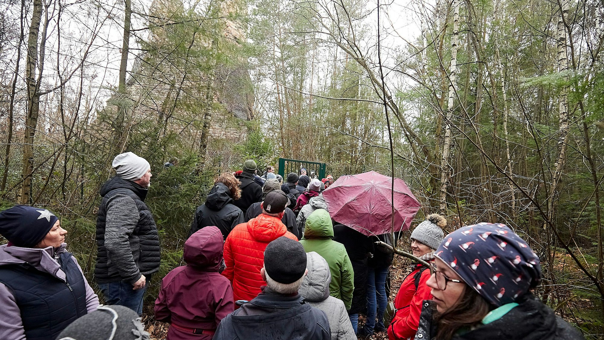 Das Bild zeigt einer Wandergruppe, die am Fundament des einst so hohen Schlots Halt gemacht hat.