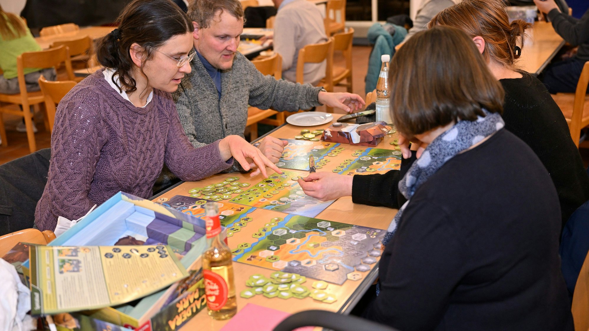 Drei Frauen und ein Mann spielen ein Brettspiel.