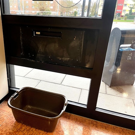 Ein Wäschekorb steht im Inneres des Kreishauses unter dem Briefschlitz.