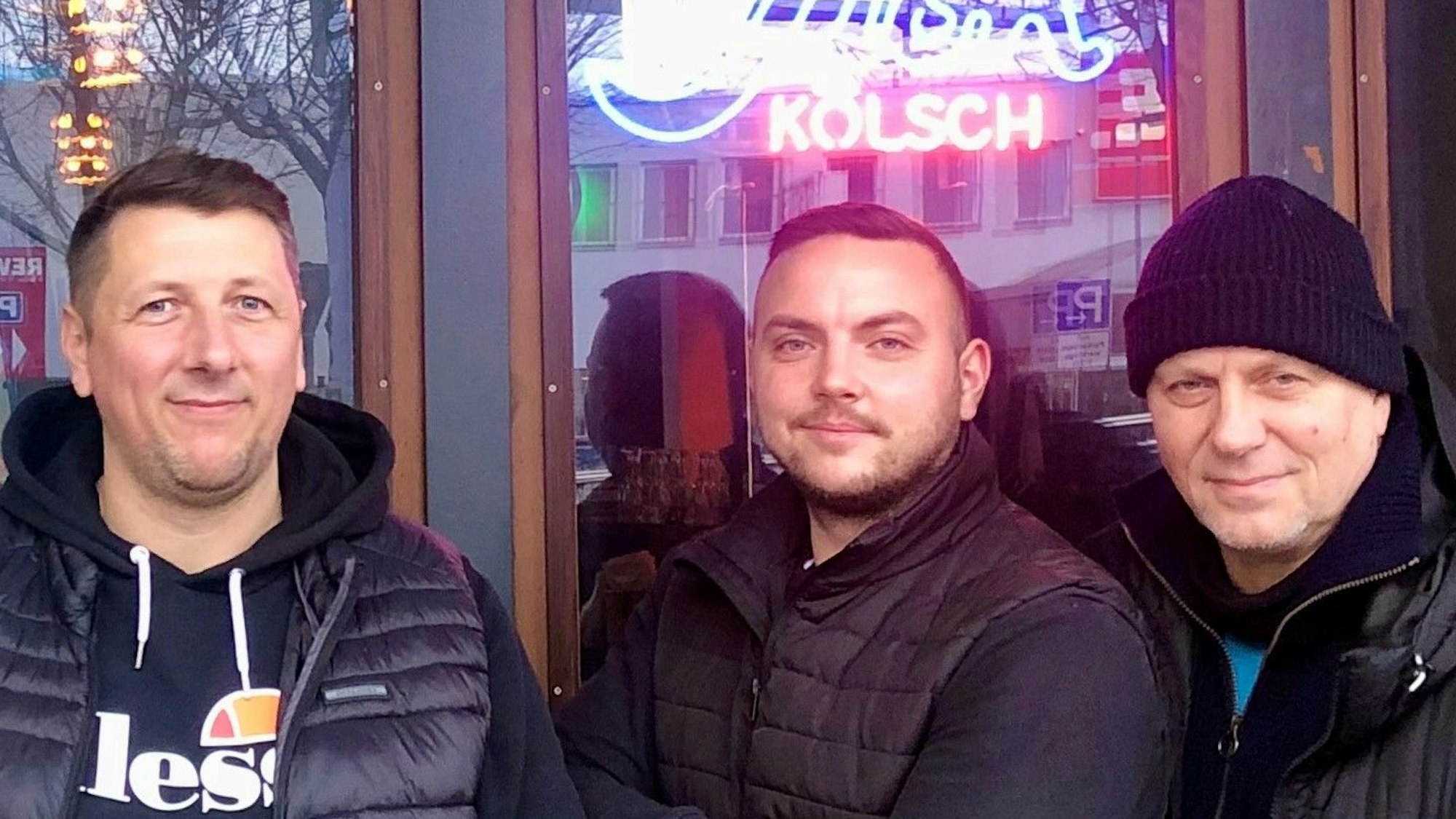 Die Köpfe dreier Männer vor einer Kneipe