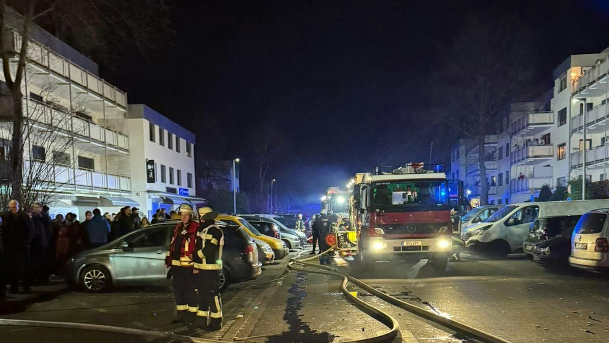 Das Bild zeigt Einsatzkräfte am Wohnpark, einen Feuerwagen, Blaulicht, umstehende Menschen.