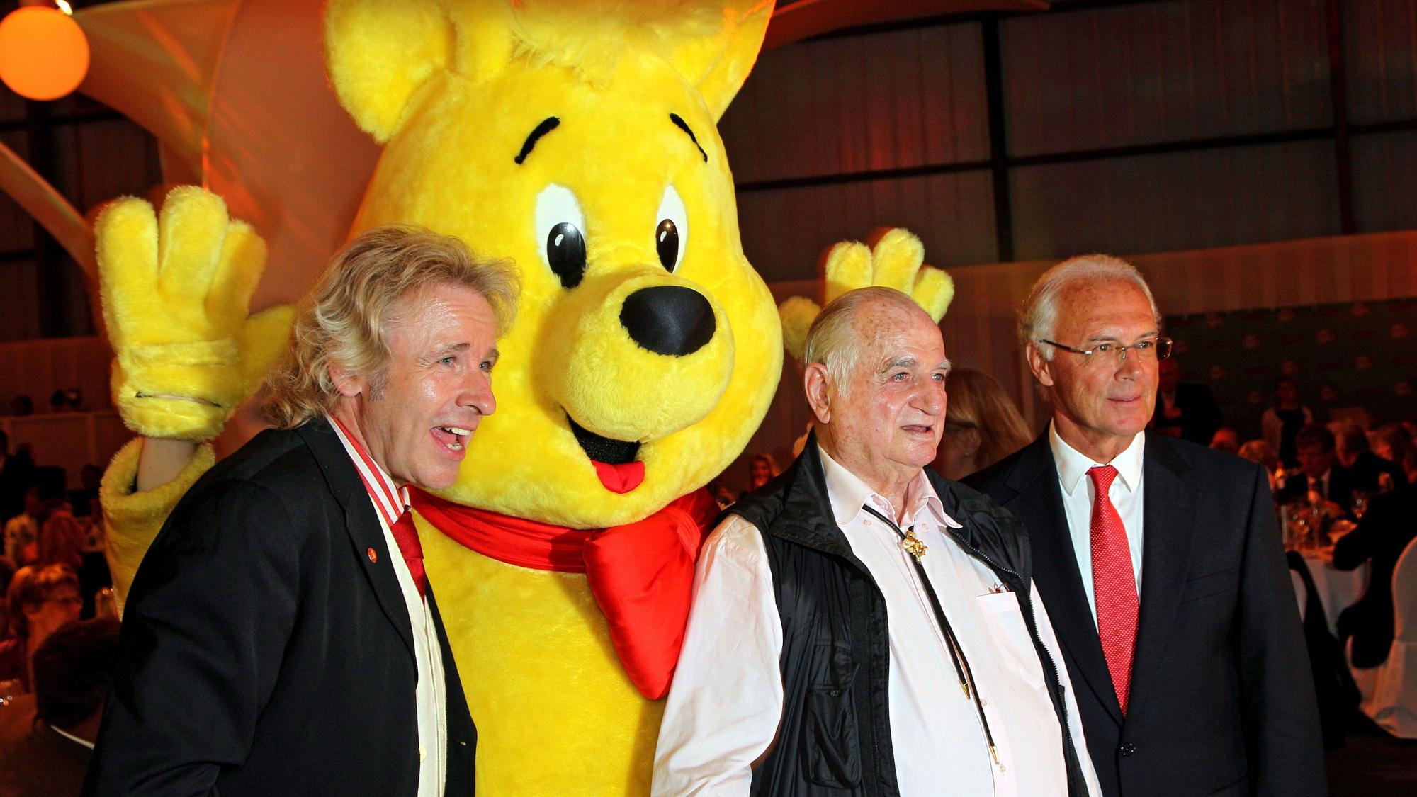 Der Moderator Thomas Gottschalk (l-r), der langjährige Haribo-Firmenchef Hans Riegel und der Ehrenpräsident des FC Bayern, Franz Beckenbauer, stehen 2010 bei der Haribo Charity Golf Challenge auf dem Golfplatz Jakobsberg bei Boppard neben dem Haribo-Goldbären.