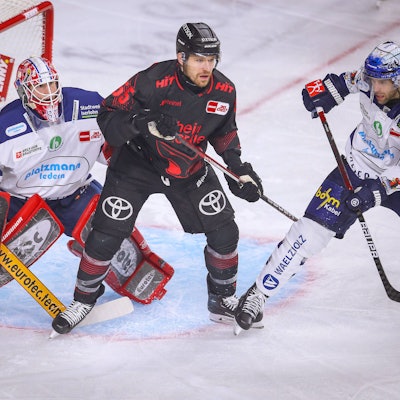 Eishockeyspieler stehen dich gedrängt vor einem Tor.