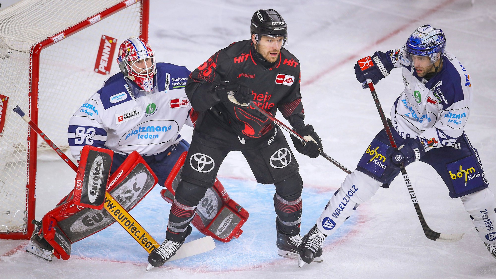 Eishockeyspieler stehen dich gedrängt vor einem Tor.