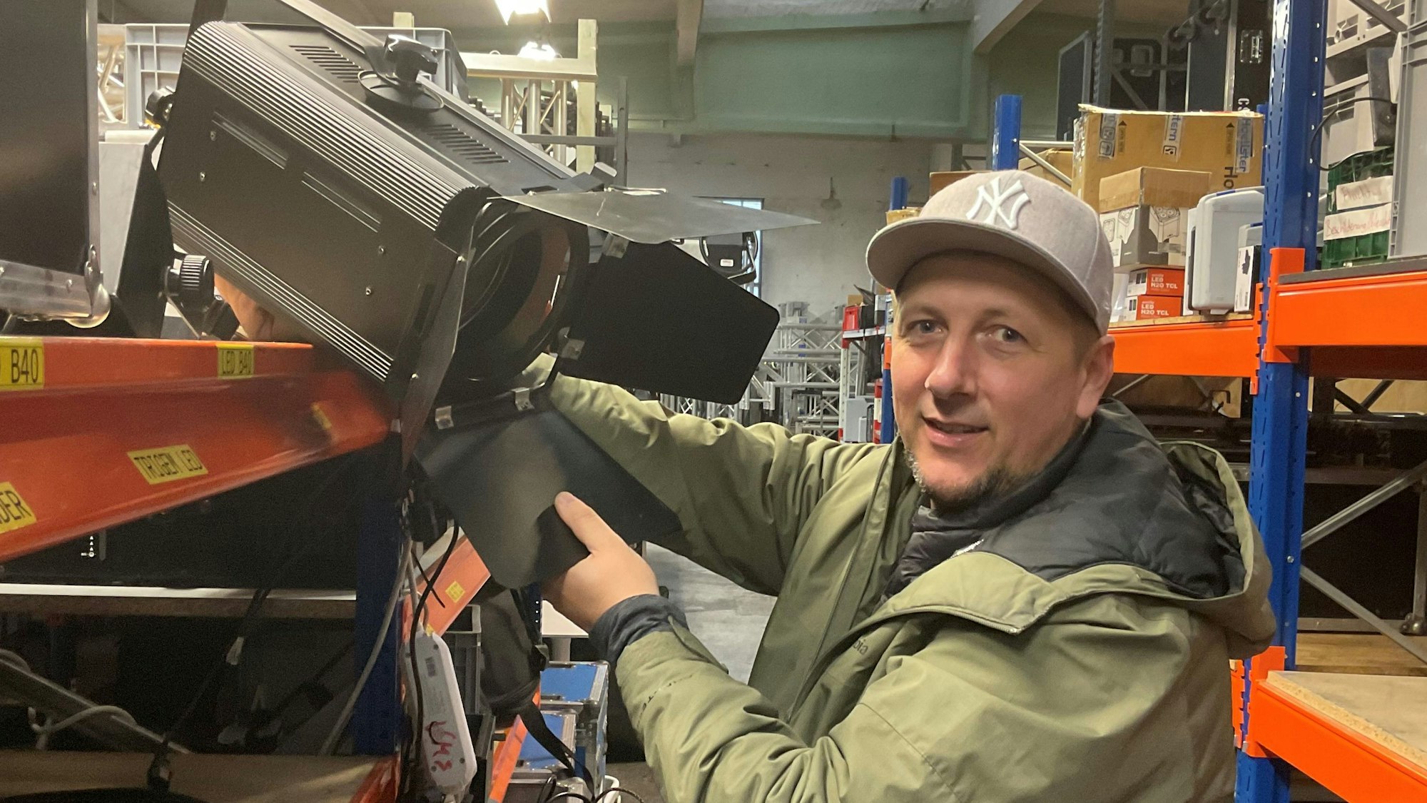 Mann holt Scheinwerfer aus einem Regal