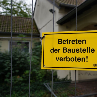 Ein gelbes Schild mit der Aufschrift „Betreten der Baustelle verboten!“ am Feuerwehrgerätehaus in Sindorf.