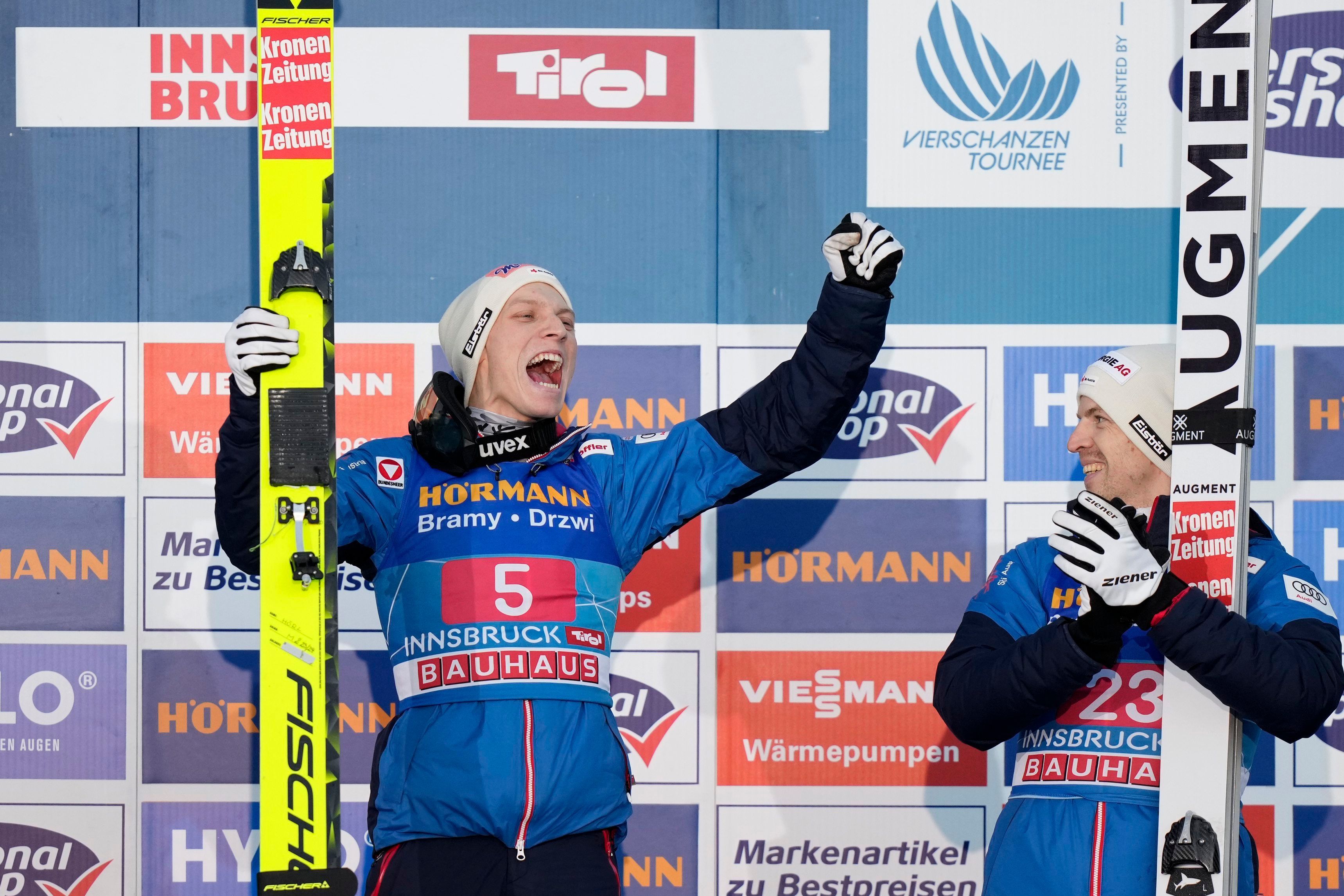Jan Hoerl, of Austria, celebrates on the podium after winning the third stage of the 72th Four Hills ski jumping tournament in Innsbruck, Austria, Wednesday, Jan. 3, 2024. At right is this placed Michael Hayboeck, also of Austria. (AP Photo/Matthias Schrader)