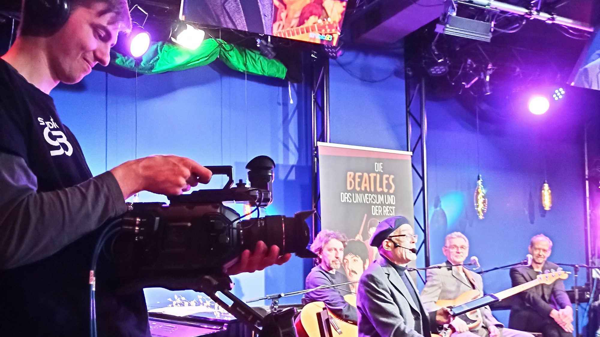 Ein junge Mann filmt Musiker auf der Bühne.