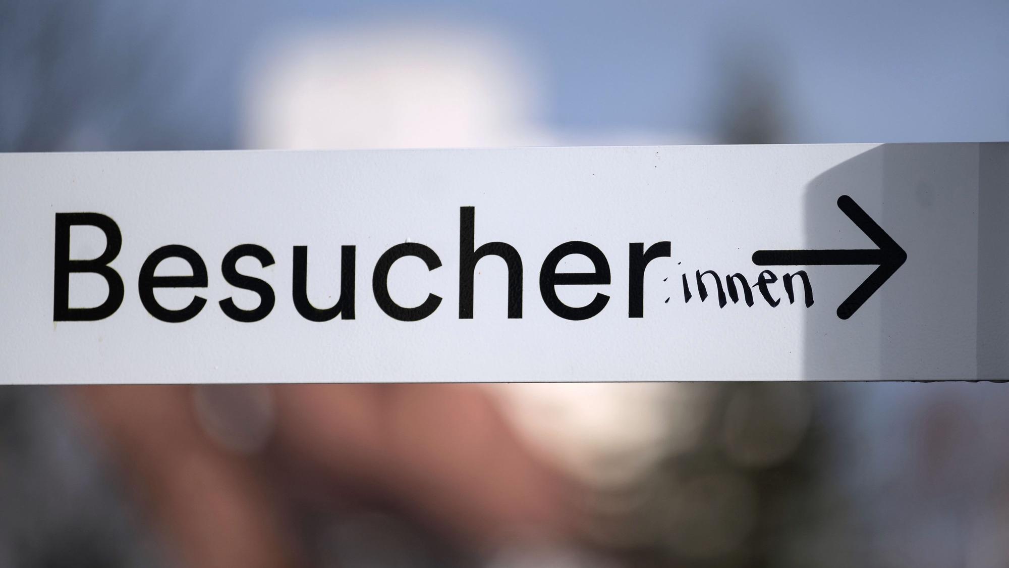 Auf einem Schild mit der Schrift „Besucher“ hat jemand handschriftlich die weibliche Form „innen“ ergänzt.