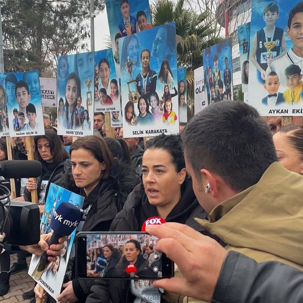 Angehörige stehen vor dem Gerichtsgebäude im südosttürkischen Adiyaman und halten Bilder ihrer Kinder hoch, dir bei dem Erdbeben im vergangenen Februar getötet wurden.
