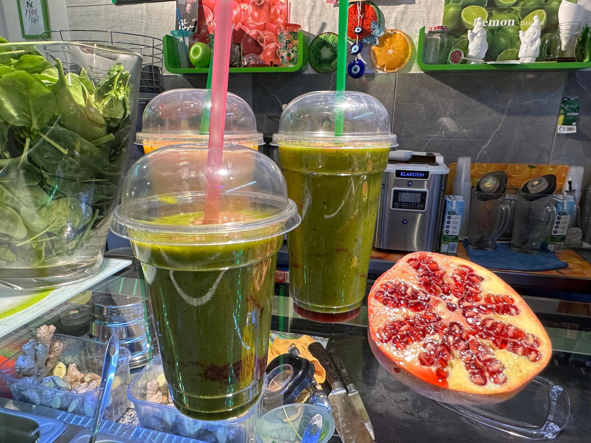 Grüne Smoothies stehen auf einem Glastresen.