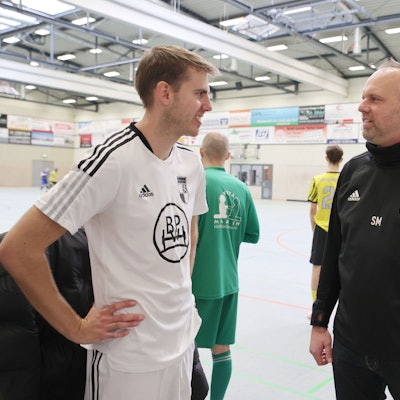 Blick auf zwei Fußballtrainer, die miteinander sprechen.