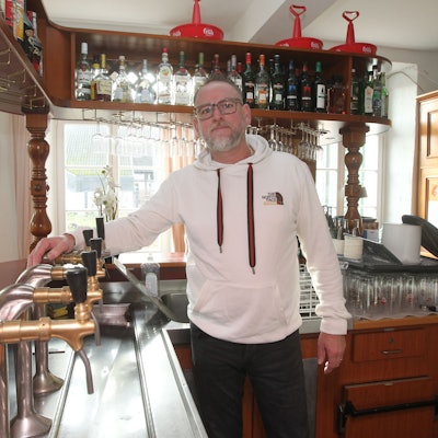 Ein Mann im Kapuzenpullover steht an einer Theke.