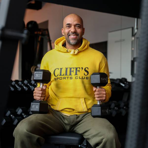 Clifford Opoku-Afari sitzt mit Hanteln in der Hand in einem Sportstudio.
