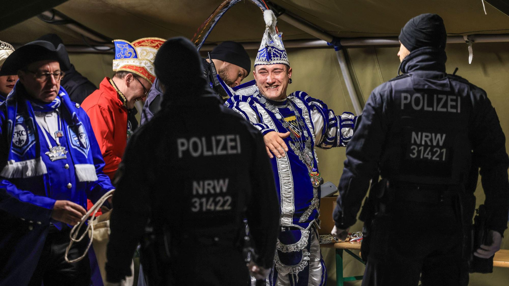 Menschen in Karnevalstrachten, die von Polizisten kontrolliert werden