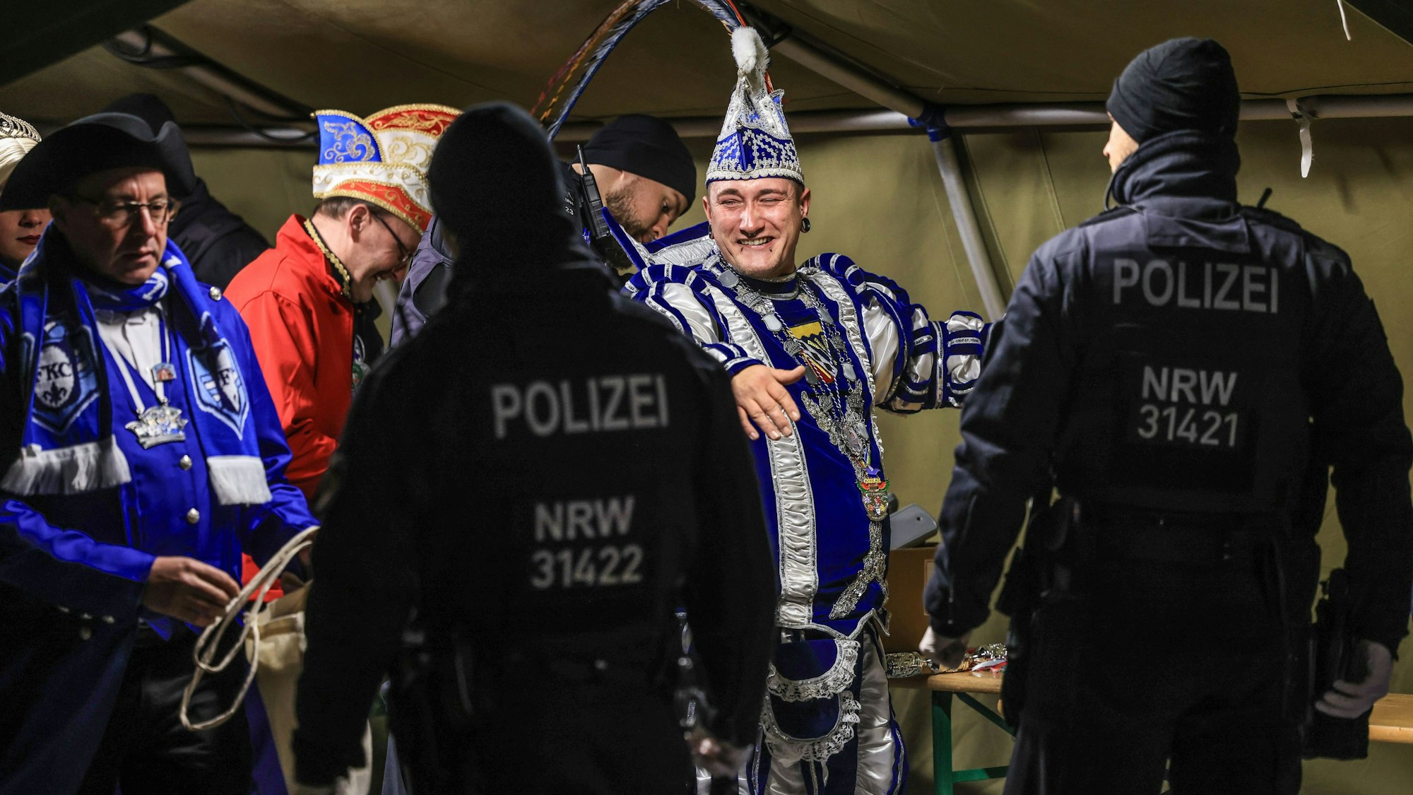 Menschen in Karnevalstrachten, die von Polizisten kontrolliert werden