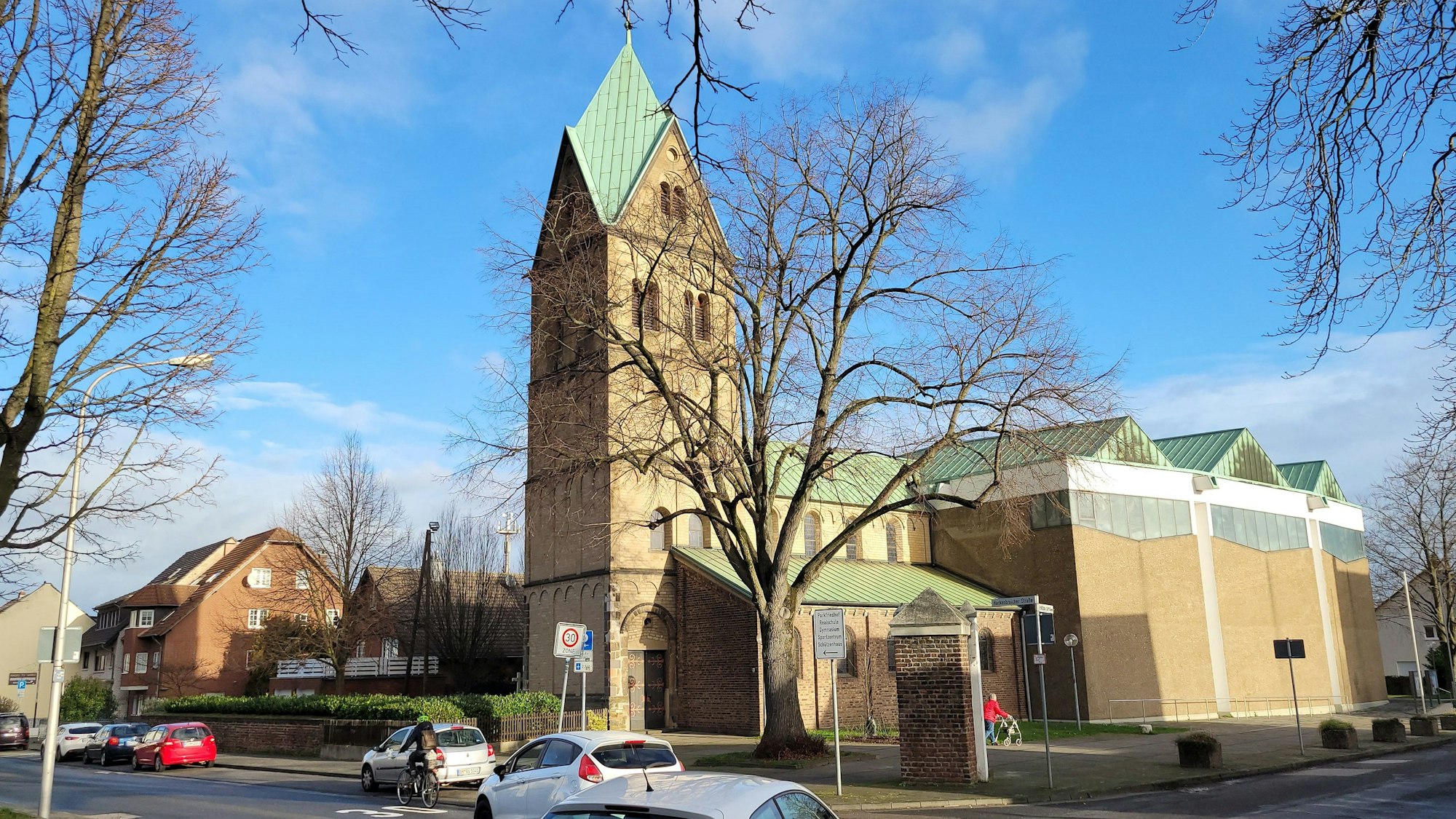 Auf einer Kreuzung  biegen zwei Fahrzeuge nach links ab, im Hintergrund ist eine Kirche zu sehen.