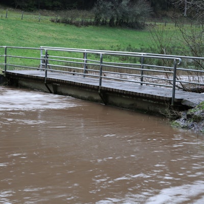 Der Wolferter Bach ist über die Ufer getreten, das Wasser steht bis n  führt Hochwasser.