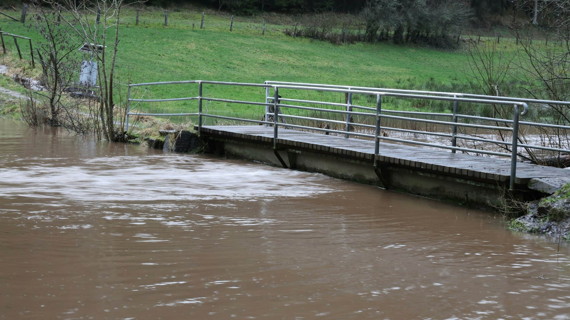 Der Wolferter Bach ist über die Ufer getreten, das Wasser steht bis n  führt Hochwasser.