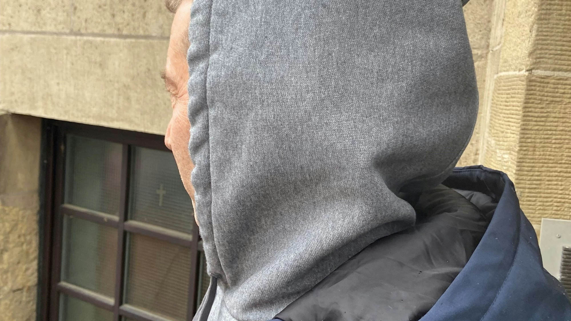 Zu sehen ist ein Mann mit Kapuze von Hinten.