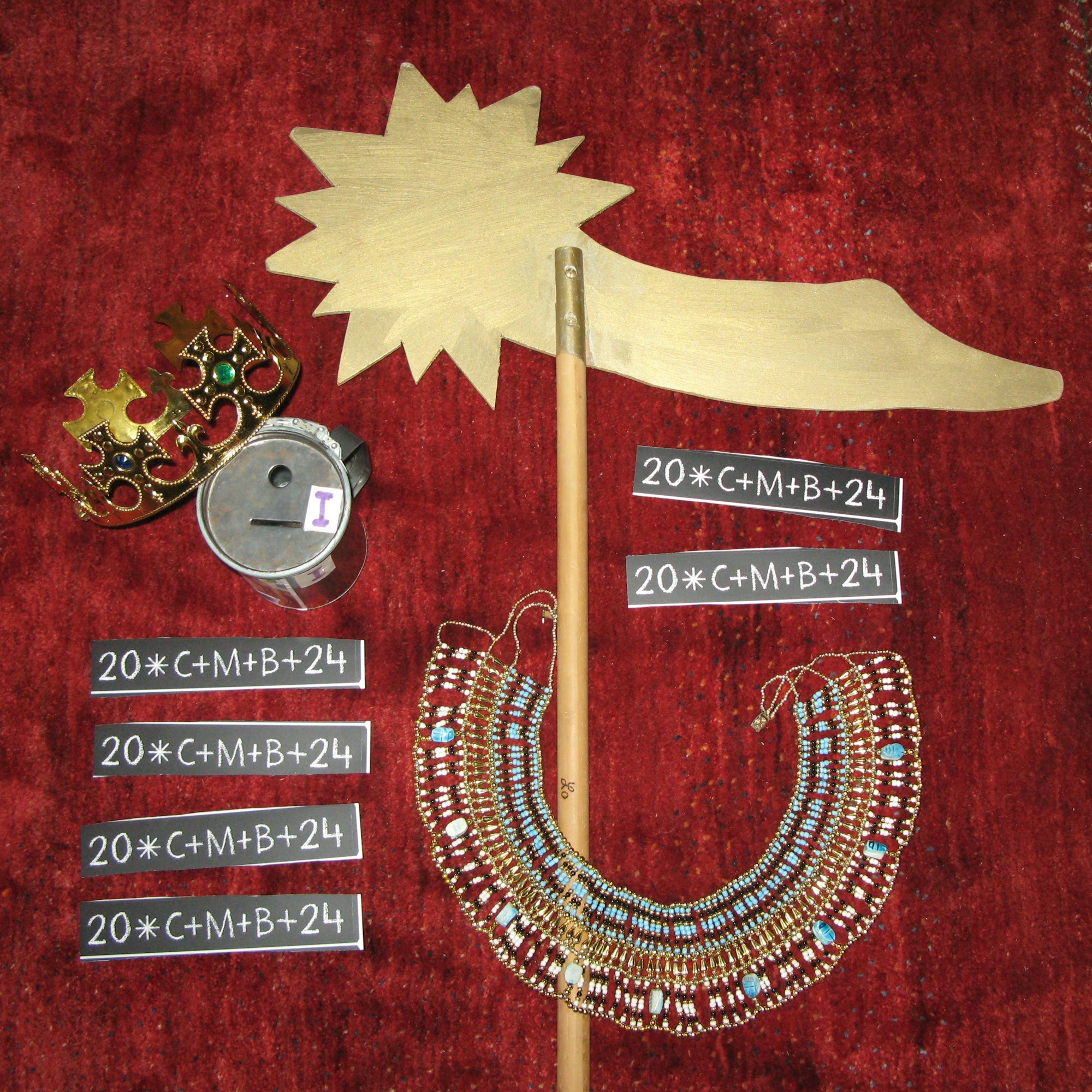 Ein Teil der Sternsinger-Ausstattung liegt auf einem roten Teppich: Krone, Stern, Halsschmuck, Aufkleber mit dem Segen und eine Spendensammeldose.